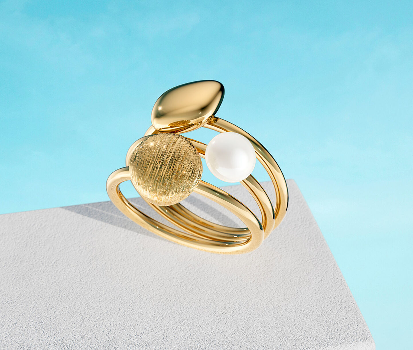 Birks Pebble yellow gold ring on a sky background.